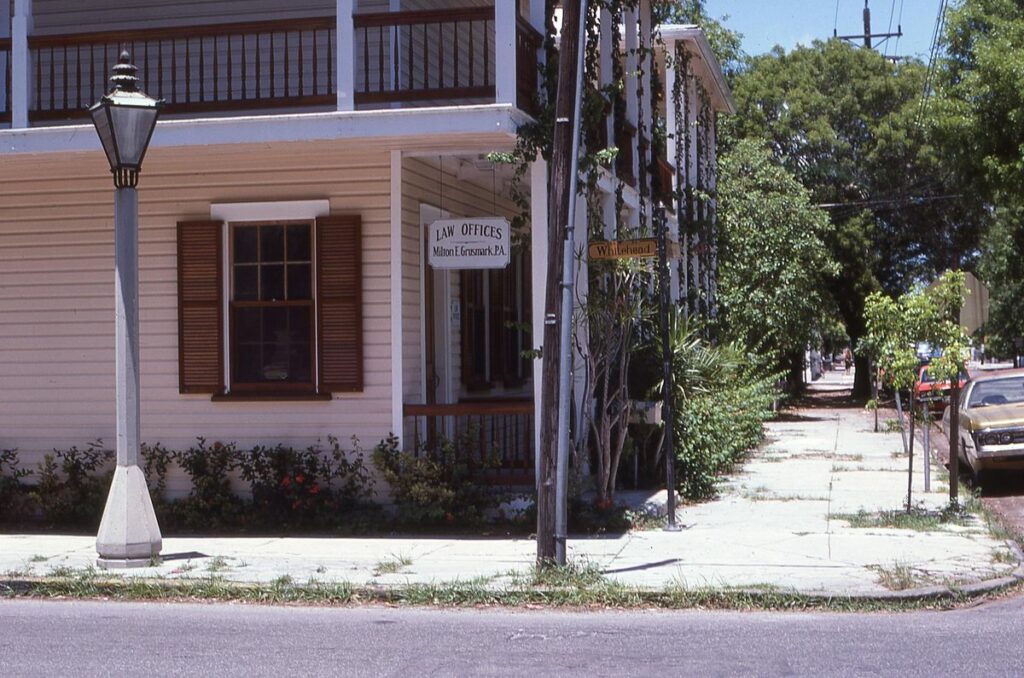 Charming historic law office with wooden shutters on a sunny corner with lush greenery.