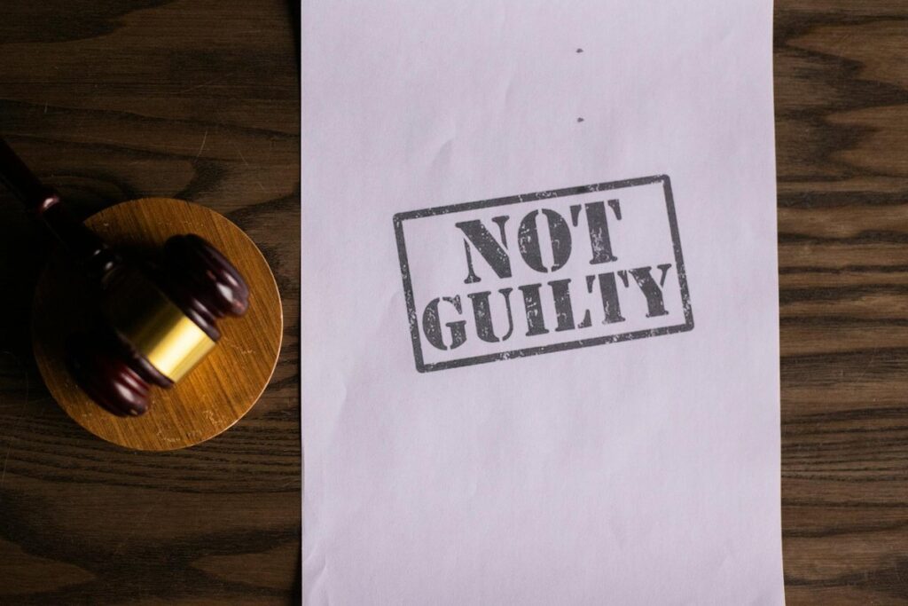 A courtroom document labeled 'Not Guilty' beside a gavel symbolizes justice.