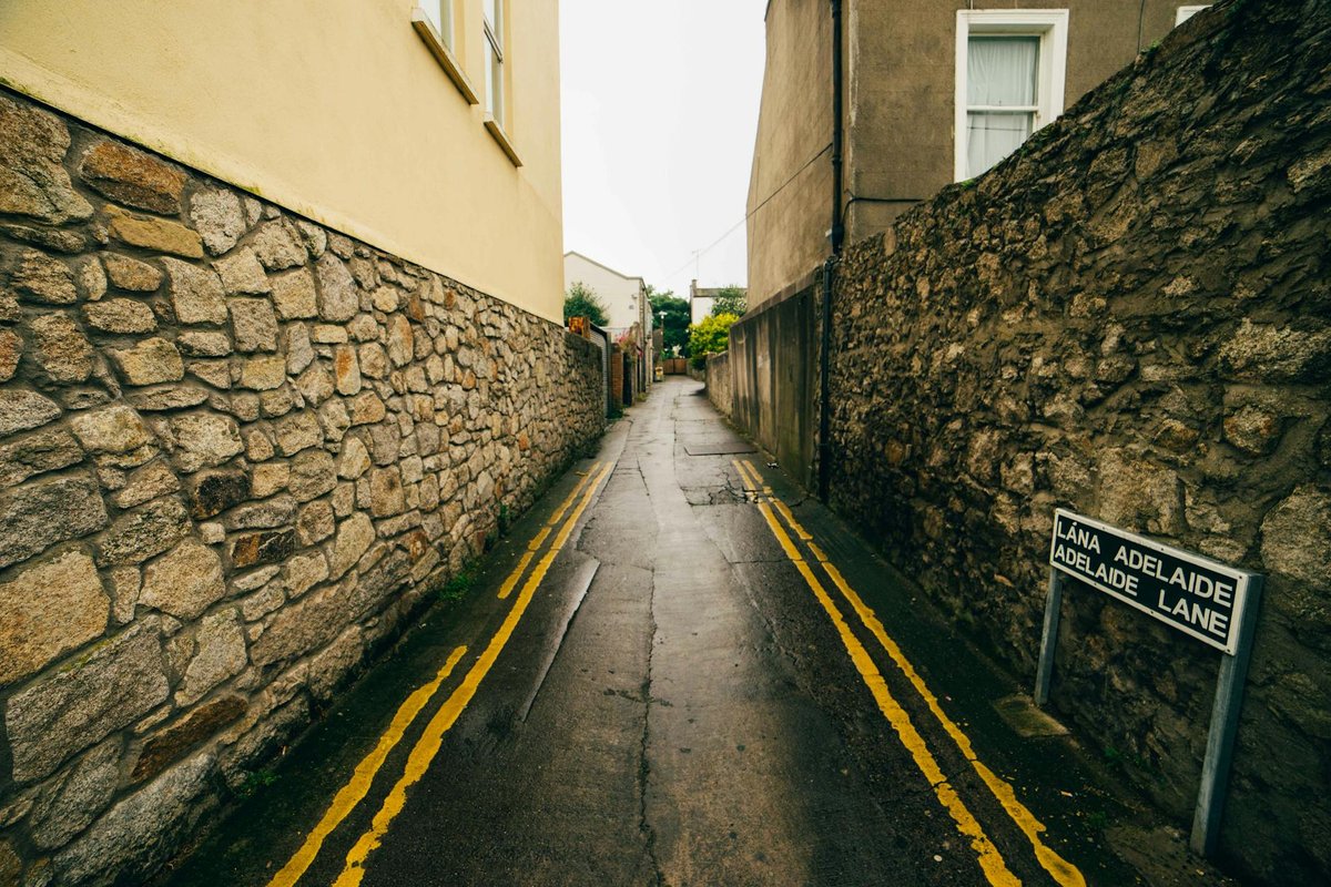 A narrow deserted alleyway in Dublin, with wet stone walls and a street sign.