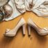 Elegant bridal high heels placed on a wooden floor with fabric accents and decor, creating a vintage wedding theme.