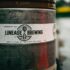 Close-up photo of a Lineage Brewing barrel with label details. Captured outdoors, offers an industrial feel.