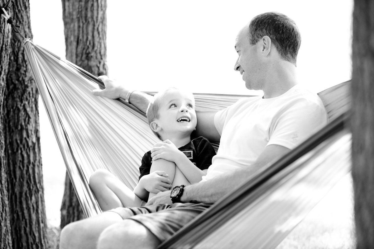 A lovely moment between father and son in a hammock, showcasing family bonding and happiness.