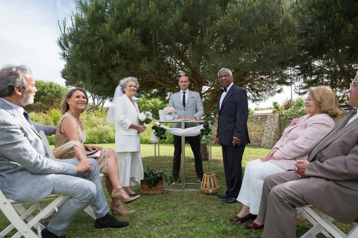 A serene outdoor wedding ceremony with senior guests and a couple in Portugal.