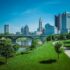 View of Columbus skyline with modern skyscrapers and green park along the river.