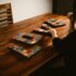 A woman arranging colorful mosaic letters on a wooden table indoors, creating art.