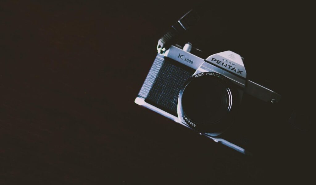 Close-up shot of a classic film camera with a dark, moody background.