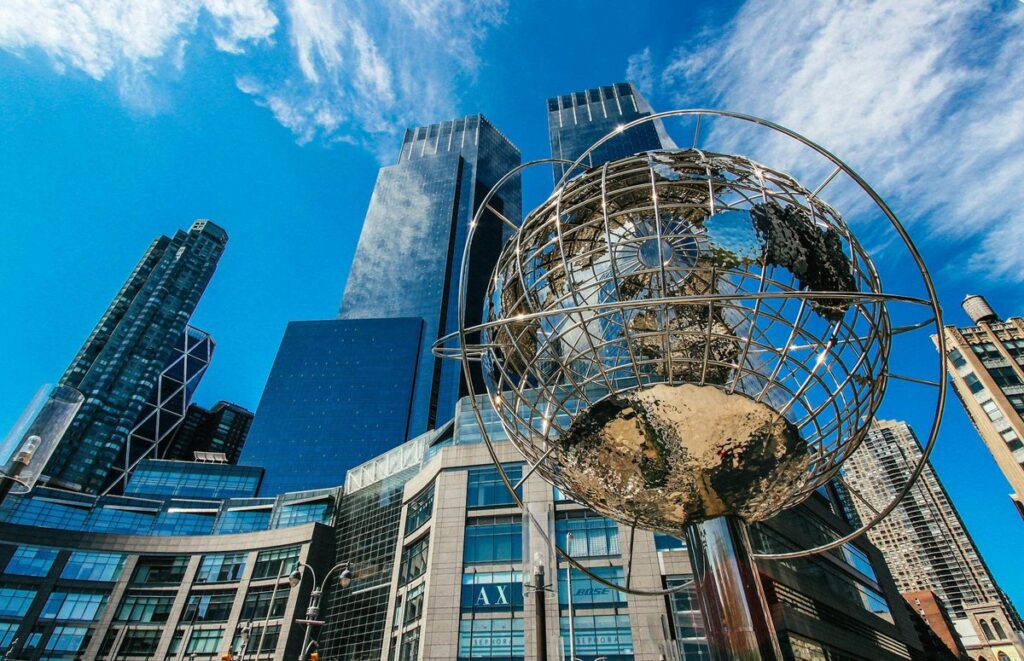 Captivating view of New York City skyline featuring a prominent globe sculpture and tall skyscrapers.