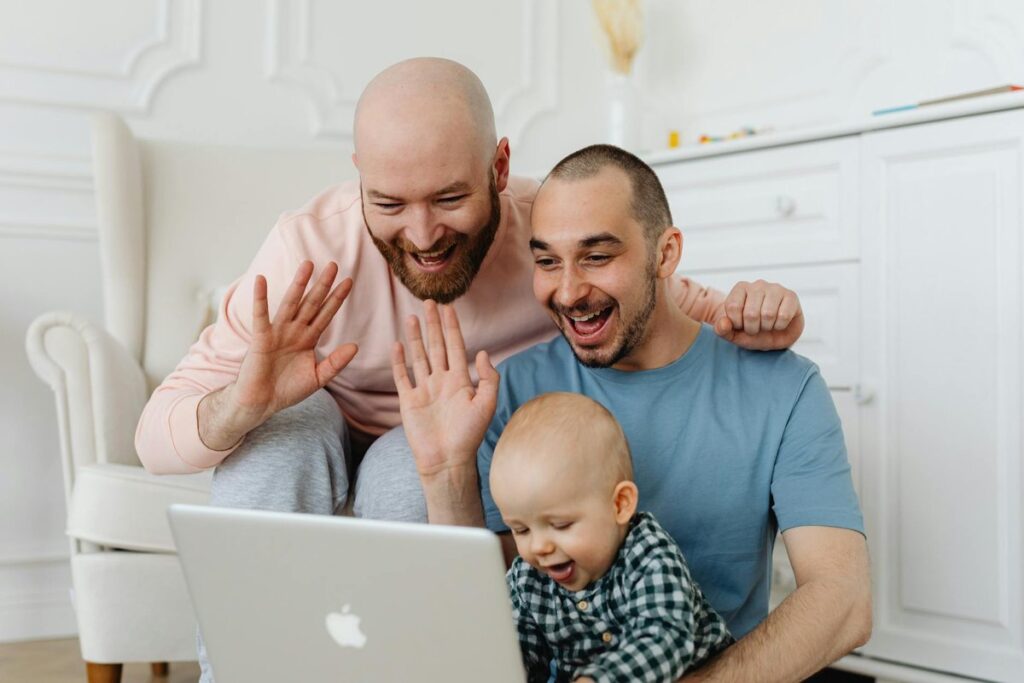 Loving same-sex couple with baby on a video call. Warm family moment.
