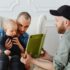 Two fathers reading a book to their toddler at home.
