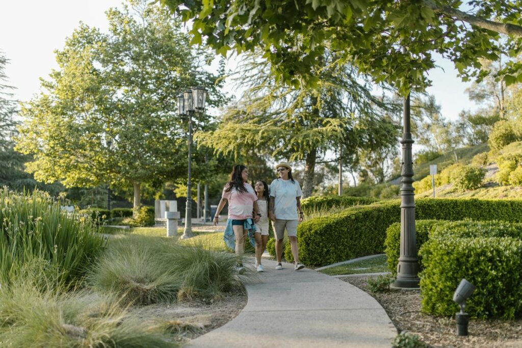 A joyful family walking together on a sunny day in the park, surrounded by greenery.