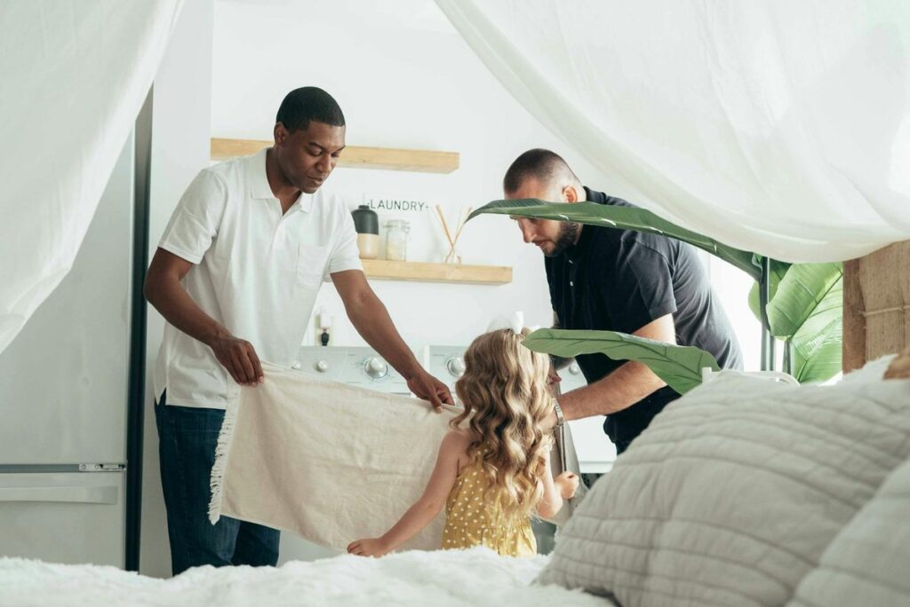 Two fathers and their daughter spending quality time together indoors, showcasing love and family unity.