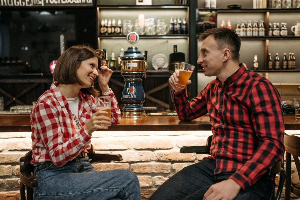 Two friends enjoying drinks and engaging in conversation at a cozy bar setting.