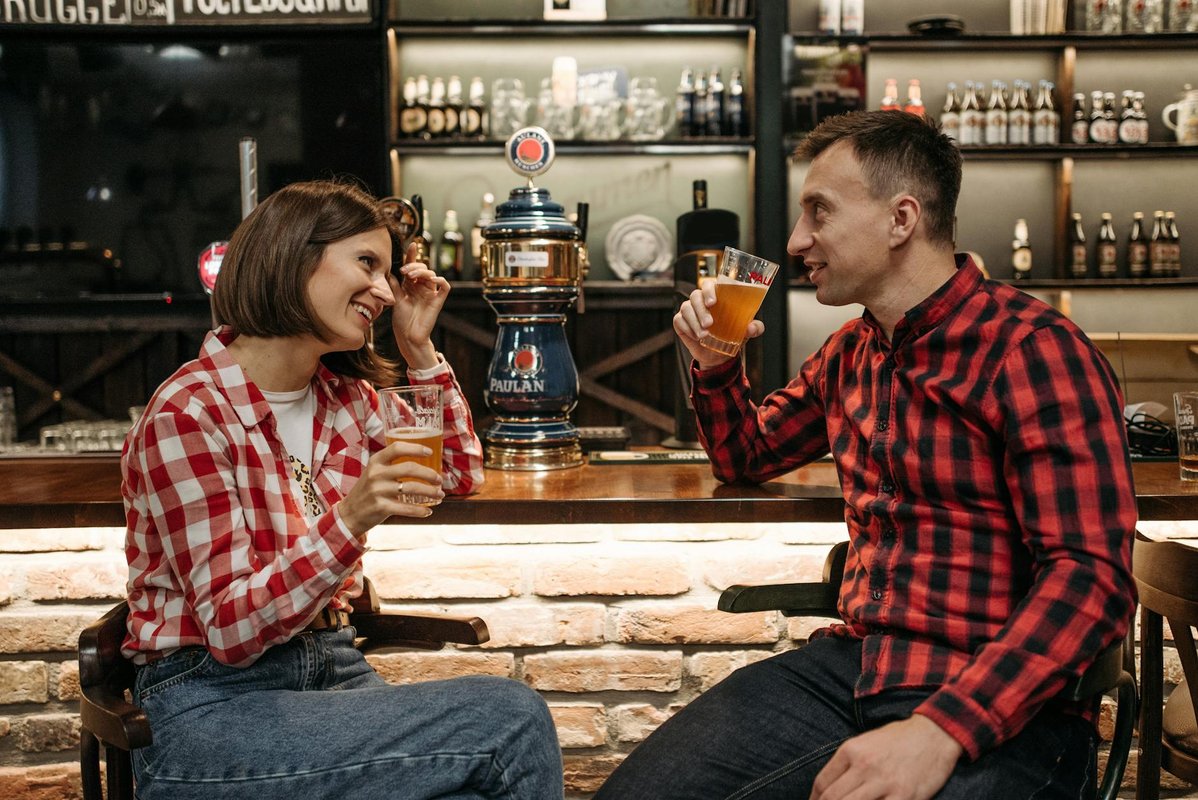 Two friends enjoying drinks and engaging in conversation at a cozy bar setting.