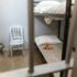 Detailed view of a clean prison cell featuring a bunk bed, metal chair, and toilet.