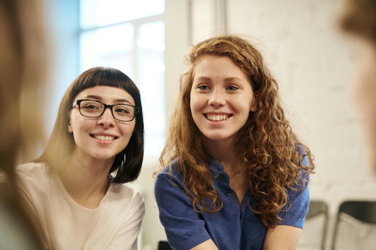 Two smiling young women indoors, conveying friendship and happiness.