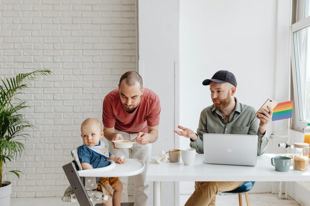 Same-sex couple enjoying breakfast with their child indoors.
