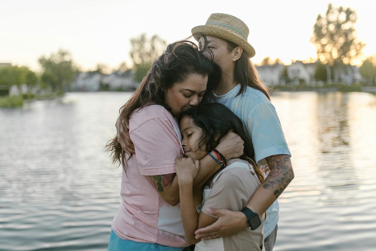 A loving family embraces by a serene lake at sunset, symbolizing warmth and unity.