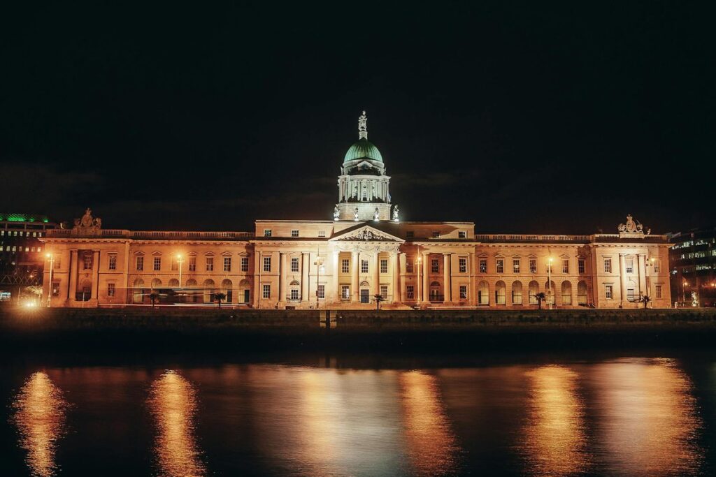 A stunning night view of the illuminated Custom House in Dublin, reflecting in the river.