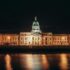A stunning night view of the illuminated Custom House in Dublin, reflecting in the river.