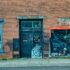 A grungy abandoned storefront with a brick facade and closed door in Millville, Minnesota.