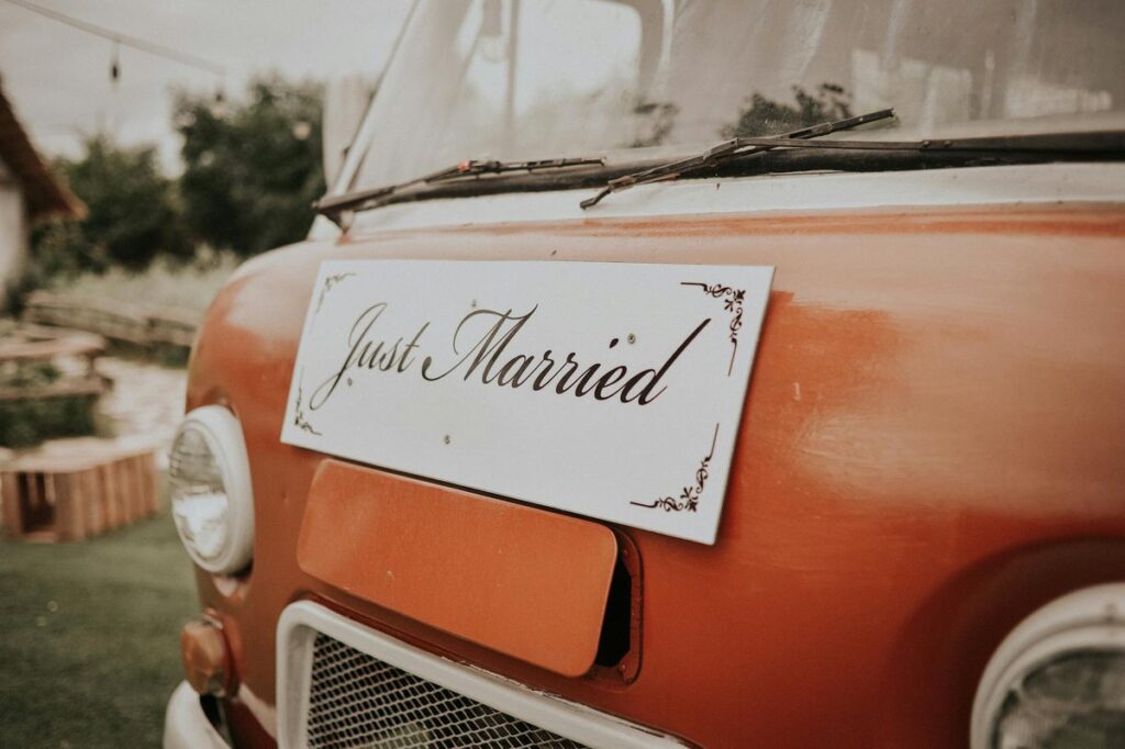 Close-up of a vintage van with a Just Married sign, symbolizing a joyful wedding celebration outdoors.