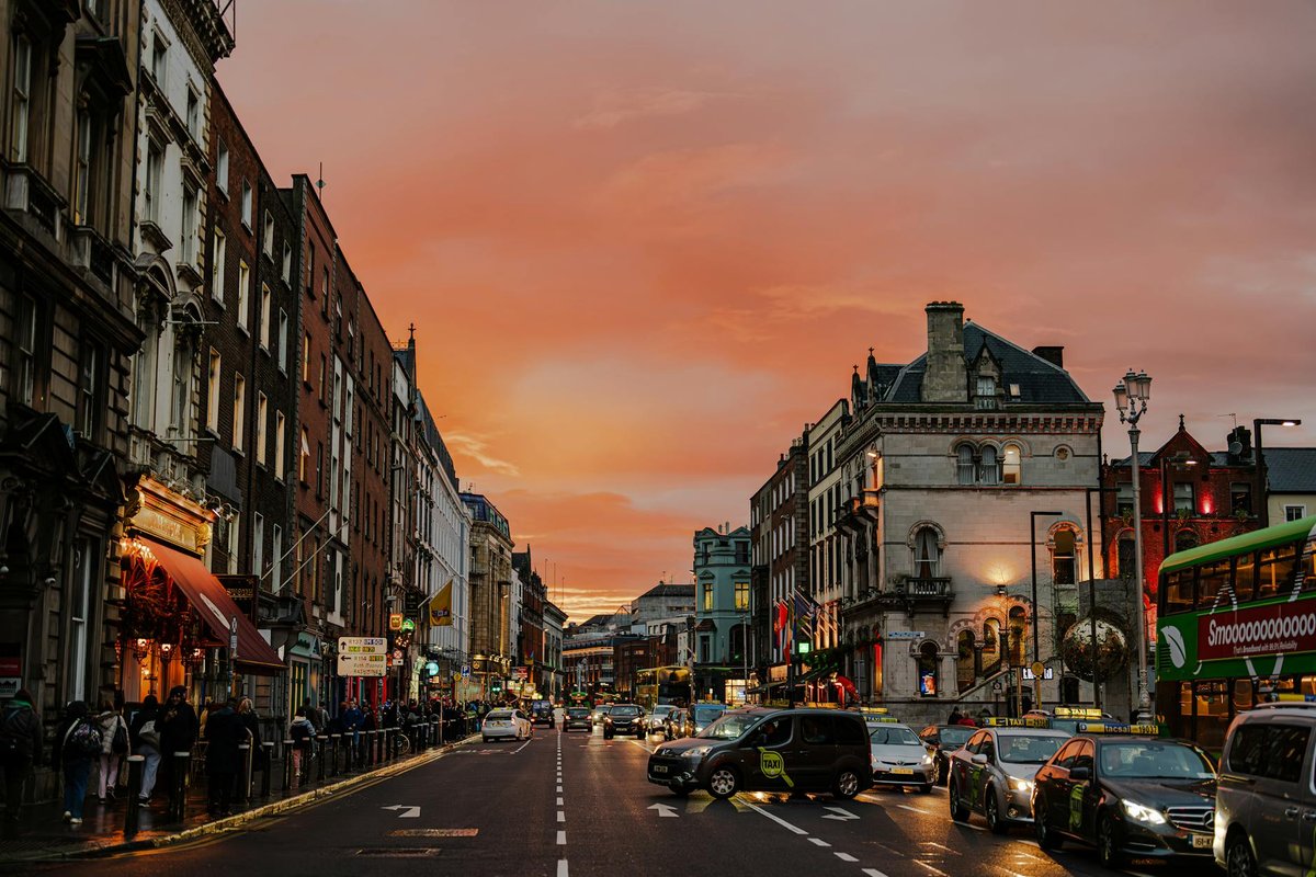 Vibrant city street in Dublin, Ireland during a stunning sunset, showcasing urban life.