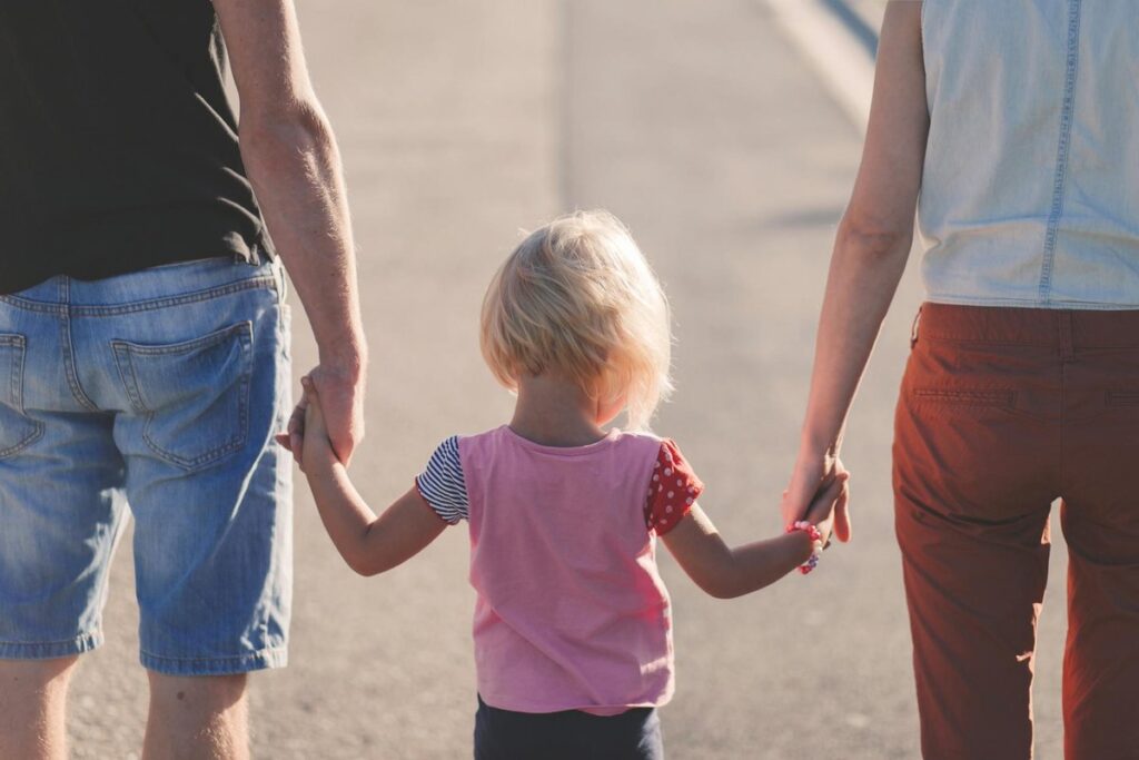 A family enjoying a sunny walk outdoors, hand-in-hand, symbolizing togetherness and love.