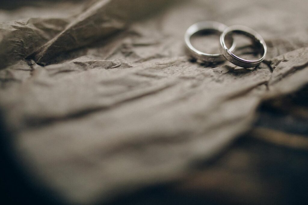 Close-up of silver wedding rings resting on crumpled paper, symbolizing commitment and marriage.