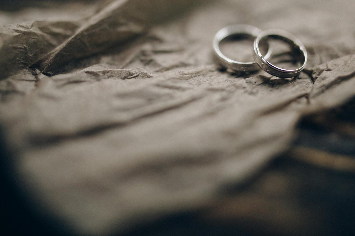 Close-up of silver wedding rings resting on crumpled paper, symbolizing commitment and marriage.