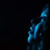 A striking portrait of a woman's side profile illuminated by blue light, creating a moody atmosphere.