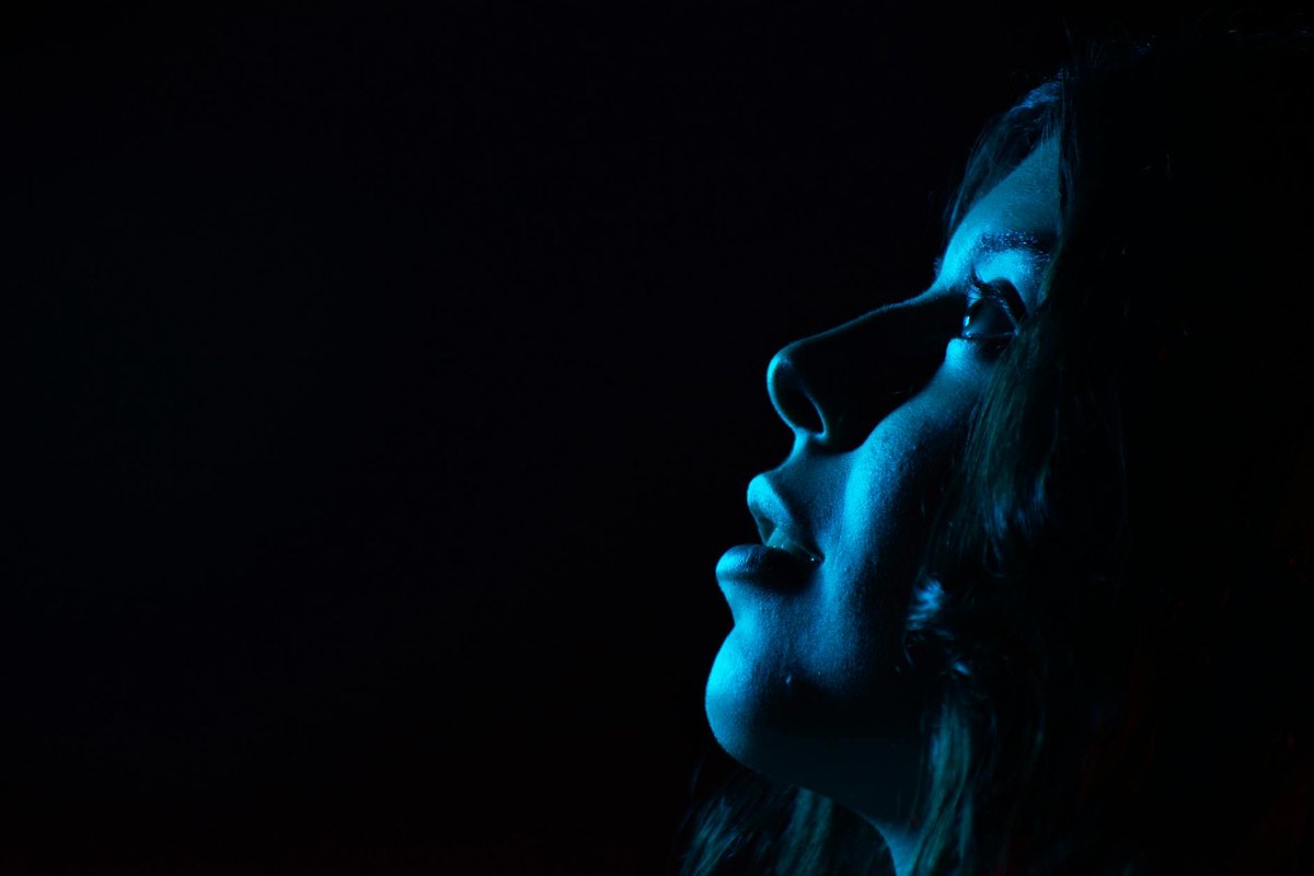 A striking portrait of a woman's side profile illuminated by blue light, creating a moody atmosphere.